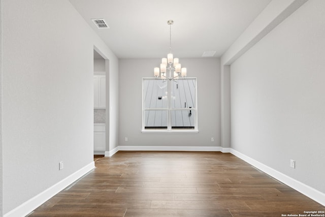 unfurnished dining area featuring an inviting chandelier and dark hardwood / wood-style floors