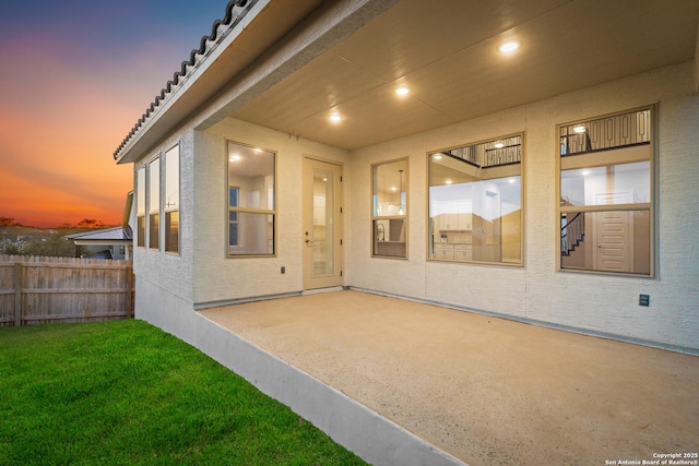 exterior entry at dusk featuring a patio area and a yard