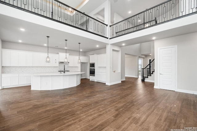 unfurnished living room with a towering ceiling and dark hardwood / wood-style floors