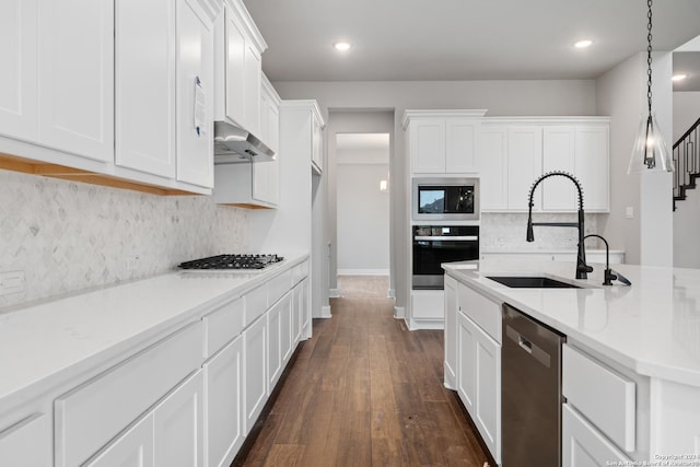 kitchen with appliances with stainless steel finishes, white cabinets, decorative light fixtures, and light stone countertops