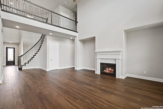 unfurnished living room featuring a towering ceiling and dark wood-type flooring