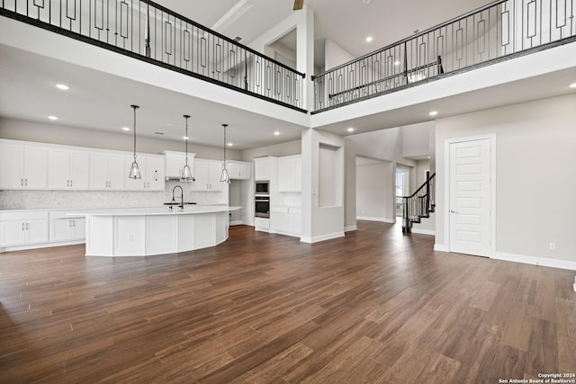 unfurnished living room featuring a high ceiling, dark wood-type flooring, and sink