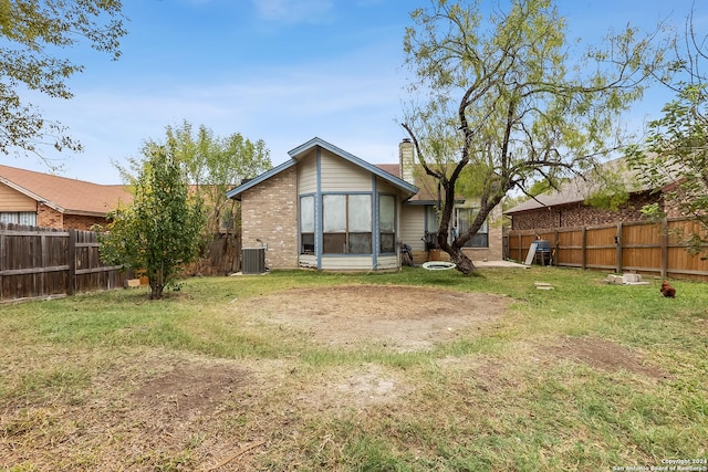 back of property with a yard and central AC unit