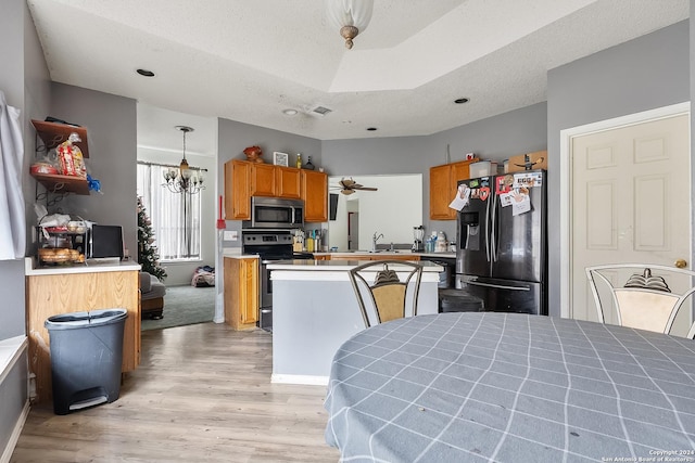 kitchen with sink, light hardwood / wood-style floors, a textured ceiling, decorative light fixtures, and appliances with stainless steel finishes