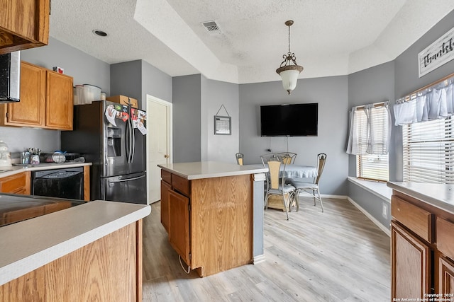 kitchen featuring pendant lighting, dishwasher, a kitchen island, a textured ceiling, and light hardwood / wood-style floors