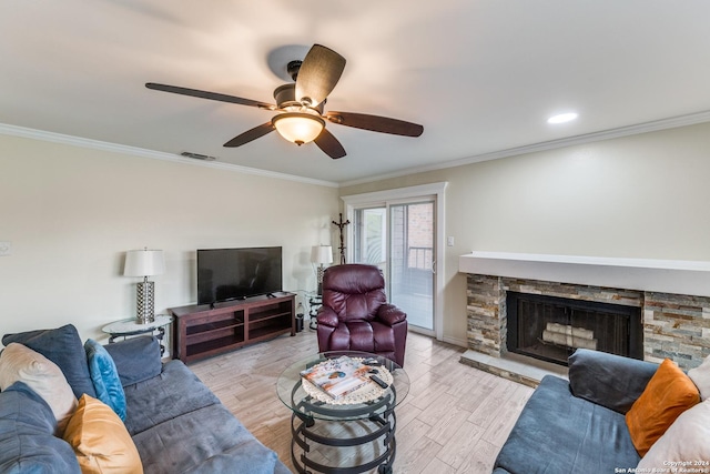 living room featuring ceiling fan, a stone fireplace, crown molding, and light hardwood / wood-style flooring