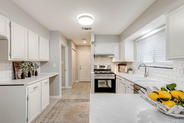 kitchen with white cabinets, sink, light hardwood / wood-style flooring, tasteful backsplash, and stainless steel appliances