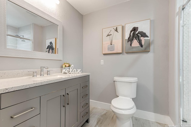 bathroom with hardwood / wood-style floors, vanity, an enclosed shower, and toilet