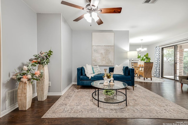 living room with dark hardwood / wood-style flooring and ceiling fan with notable chandelier