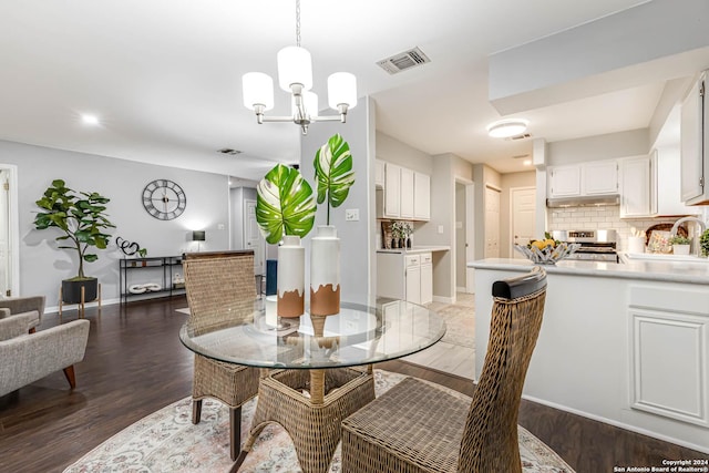 dining space featuring dark hardwood / wood-style floors, sink, and an inviting chandelier