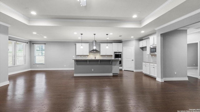 unfurnished living room featuring dark hardwood / wood-style flooring, a tray ceiling, and crown molding