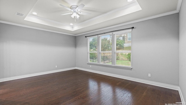 empty room with a raised ceiling, ceiling fan, dark wood-type flooring, and ornamental molding