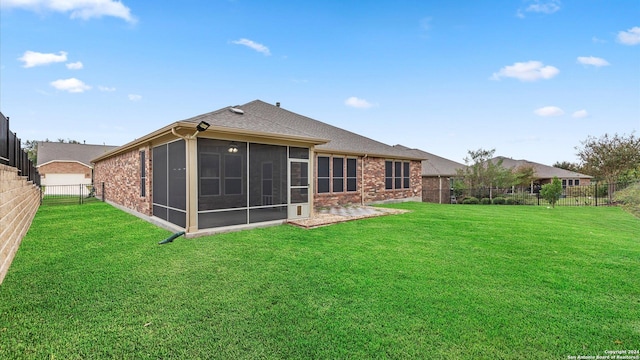 rear view of house featuring a sunroom and a yard