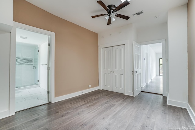 unfurnished bedroom with ensuite bath, ceiling fan, a closet, and light wood-type flooring