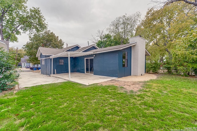 rear view of property featuring a lawn and a patio area