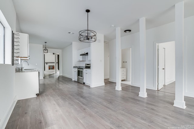 unfurnished living room with a chandelier, sink, and light hardwood / wood-style floors