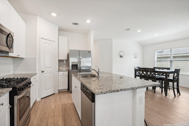 kitchen featuring appliances with stainless steel finishes, light wood-type flooring, tasteful backsplash, a kitchen island with sink, and white cabinets