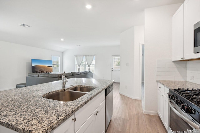 kitchen with stone counters, white cabinetry, and sink