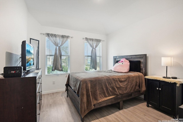 bedroom with lofted ceiling and light wood-type flooring