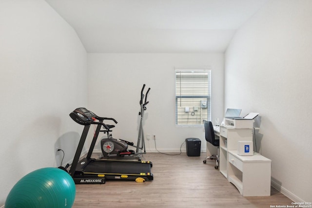 exercise room featuring vaulted ceiling and light hardwood / wood-style flooring