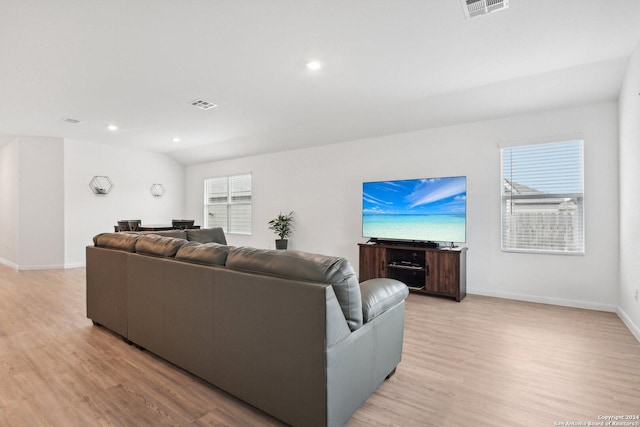 living room with a wealth of natural light, lofted ceiling, and light wood-type flooring