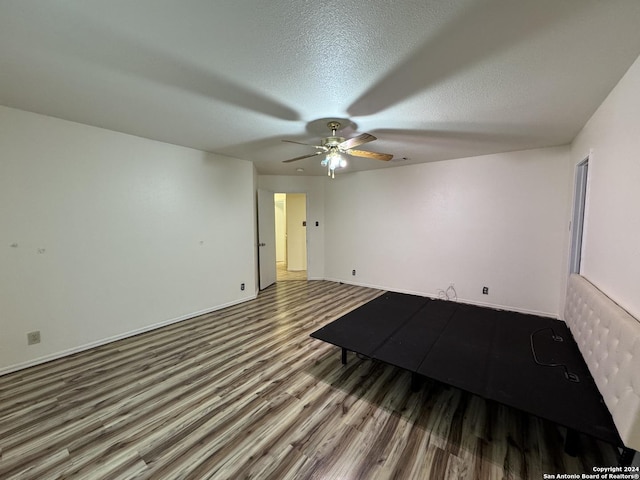 interior space featuring ceiling fan, wood-type flooring, and a textured ceiling