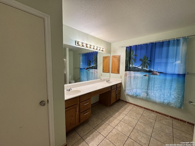 bathroom with tile patterned flooring, vanity, a textured ceiling, and toilet