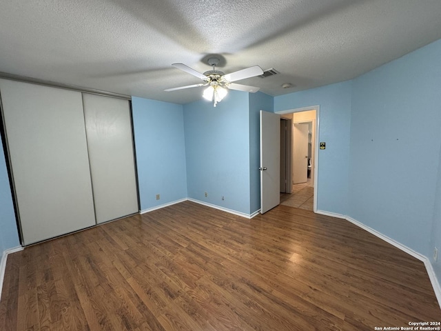 unfurnished bedroom with dark hardwood / wood-style floors, ceiling fan, a textured ceiling, and a closet