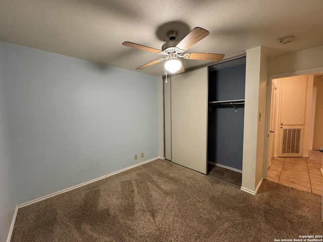 unfurnished bedroom with carpet, ceiling fan, a textured ceiling, and a closet