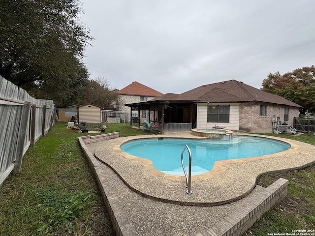 view of pool with an in ground hot tub, a yard, and a storage shed