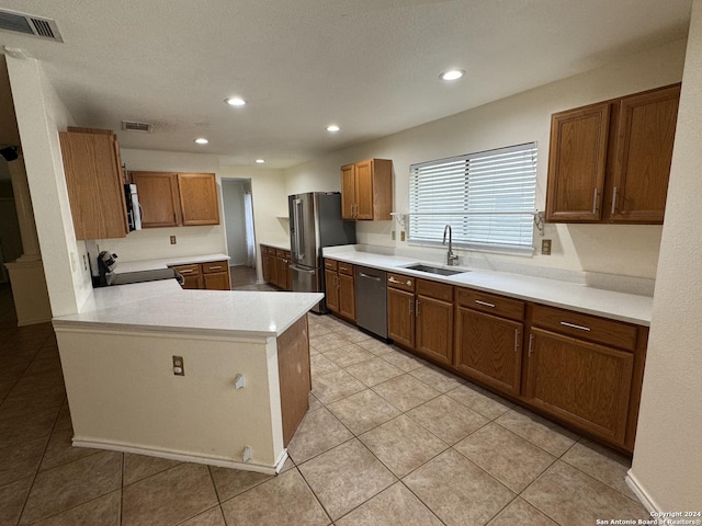 kitchen with sink, stainless steel appliances, kitchen peninsula, a textured ceiling, and light tile patterned floors