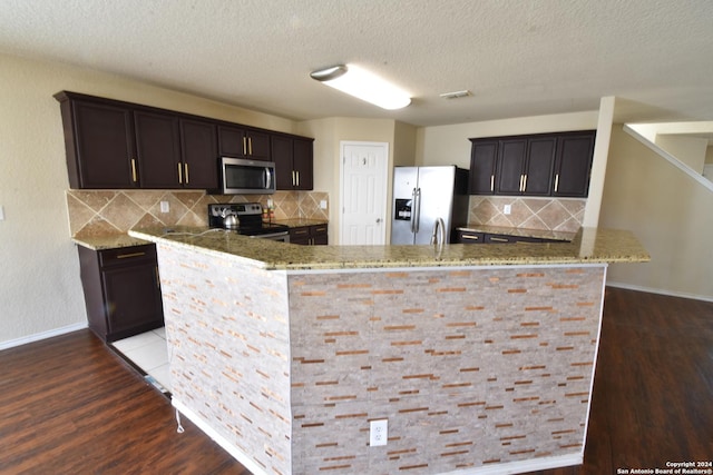 kitchen with decorative backsplash, appliances with stainless steel finishes, dark hardwood / wood-style floors, and stone countertops