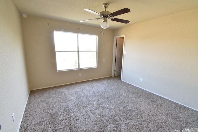 carpeted empty room featuring ceiling fan and a textured ceiling