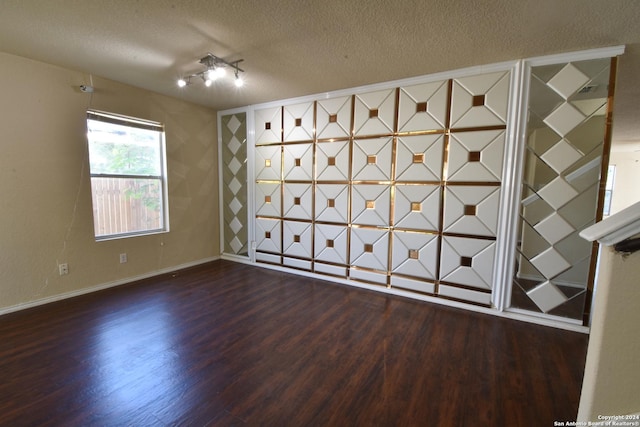 unfurnished room featuring a textured ceiling and dark hardwood / wood-style floors