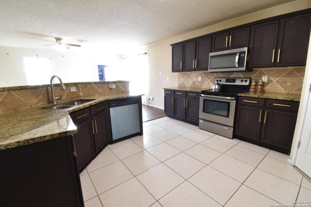 kitchen featuring sink, ceiling fan, light stone countertops, a textured ceiling, and stainless steel appliances