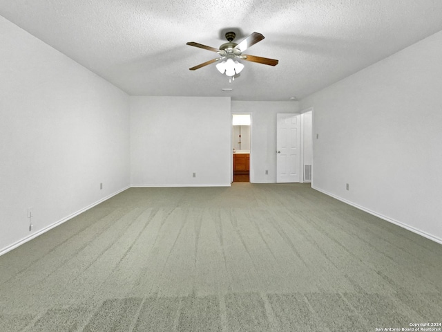 empty room with carpet flooring, ceiling fan, and a textured ceiling