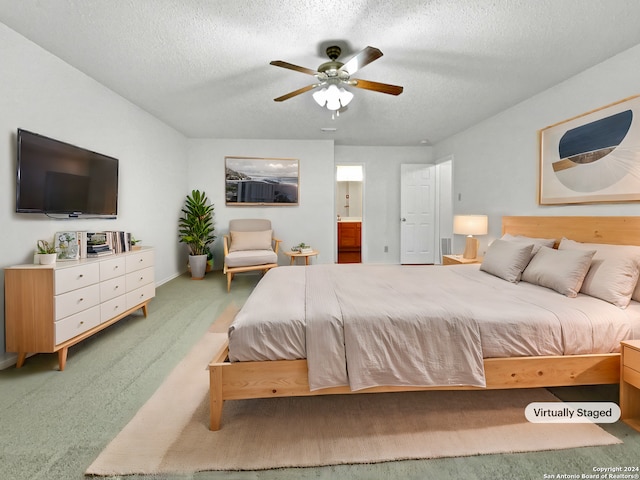 carpeted bedroom with ceiling fan, a textured ceiling, and ensuite bath