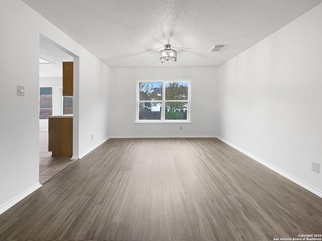 empty room with a textured ceiling and dark hardwood / wood-style floors