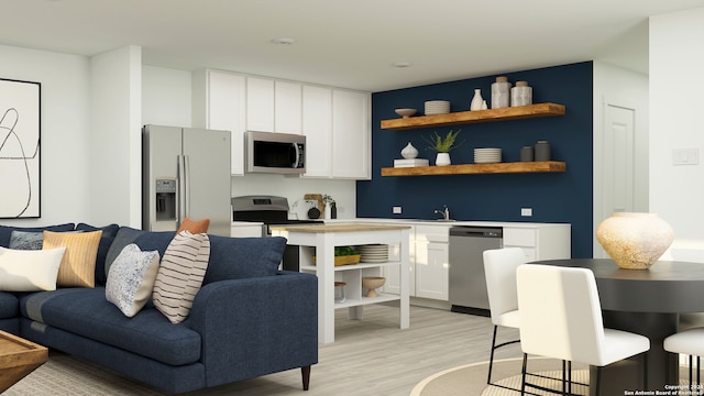 interior space with appliances with stainless steel finishes, light hardwood / wood-style floors, white cabinetry, and sink