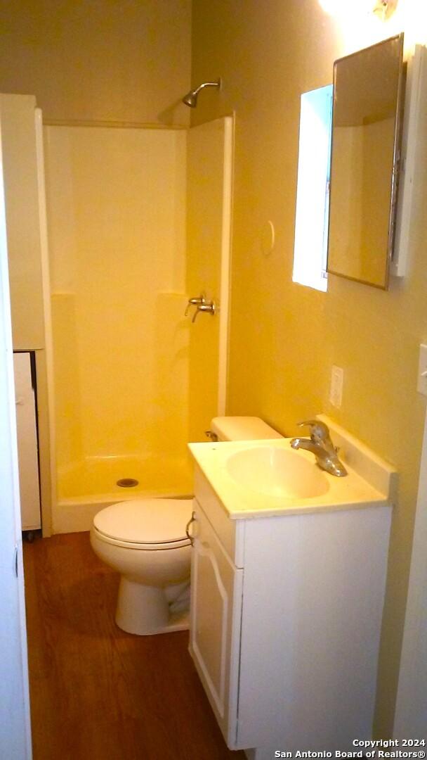 bathroom featuring toilet, vanity, wood-type flooring, and walk in shower