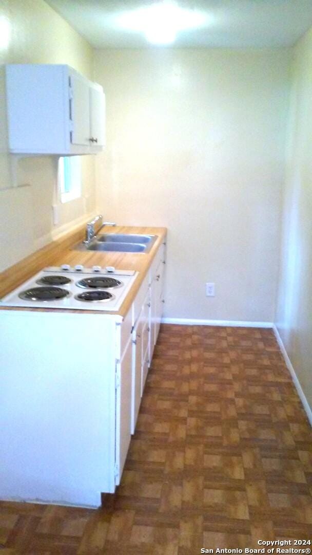 kitchen featuring dark parquet floors, sink, white cabinets, and white cooktop