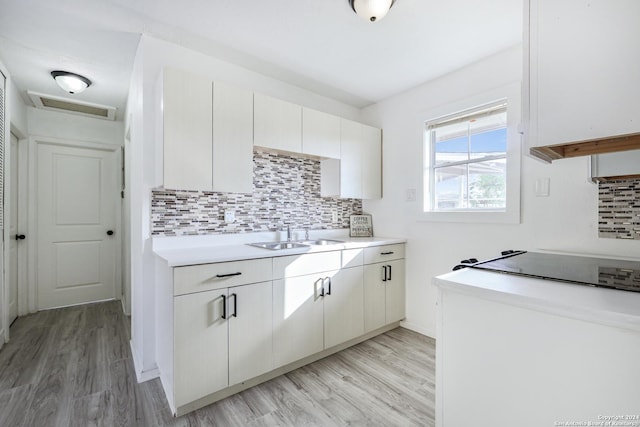 kitchen featuring light wood-type flooring, white cabinetry, sink, and tasteful backsplash