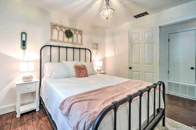 bedroom with a chandelier and dark wood-type flooring