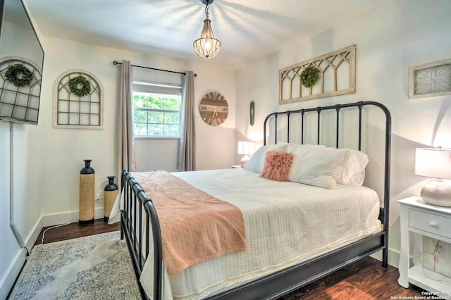 bedroom with a notable chandelier and dark wood-type flooring