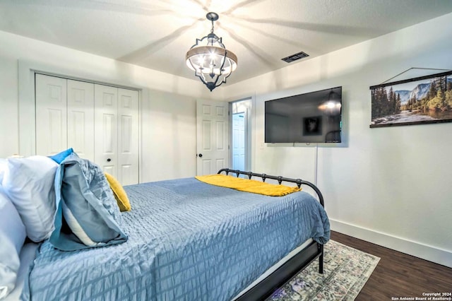 bedroom with an inviting chandelier, dark wood-type flooring, and a closet