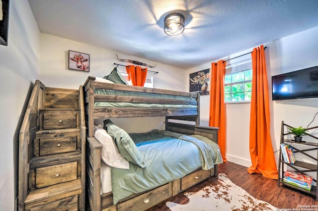 bedroom featuring a textured ceiling and dark hardwood / wood-style flooring