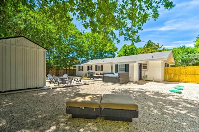 back of house with a shed, a patio, and a hot tub