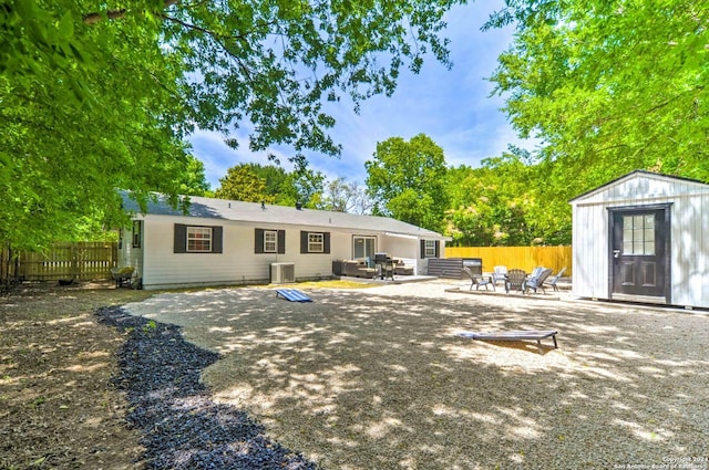 rear view of property featuring central AC unit, a storage shed, a patio, and an outdoor fire pit