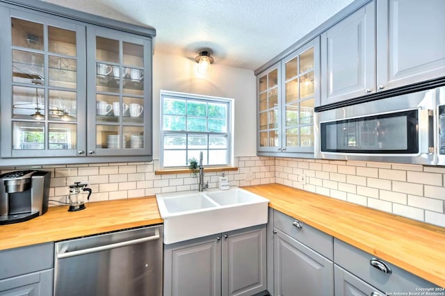 kitchen with decorative backsplash, appliances with stainless steel finishes, butcher block counters, and sink