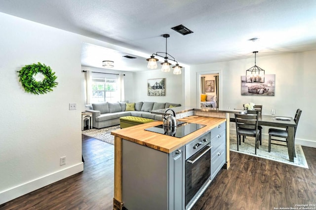 kitchen featuring wood counters, black electric stovetop, a kitchen island, dark wood-type flooring, and oven